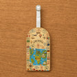 Étiquette bagage simili cuir carte du monde vintage Bon Voyage posée sur fond bois vue détail