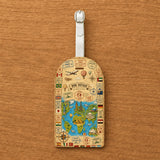 Étiquette bagage simili cuir carte du monde vintage Bon Voyage posée sur fond bois vue détail