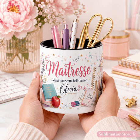Pot à crayons maîtresse fleuri personnalisé tenu en mains au-dessus d'un bureau aux accessoires dorés