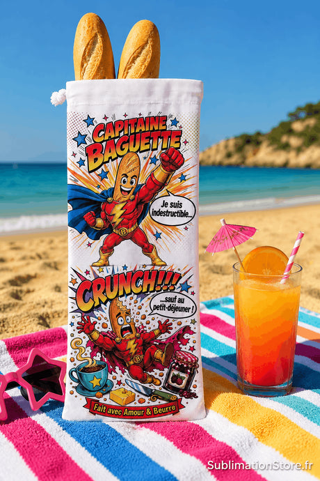Sac à baguettes Capitaine Baguette debout sur serviette rayée avec cocktail tropical et mer turquoise en arrière-plan