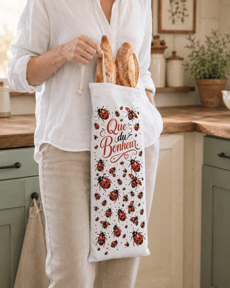Femme tenant sac à baguettes Que du Bonheur coccinelles dans cuisine
