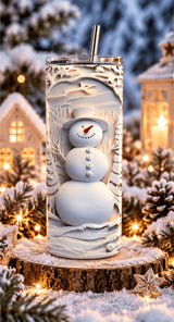 Tumbler bonhomme de neige posé sur une rondelle de bois enneigée, entre maisons illuminées et pommes de pin