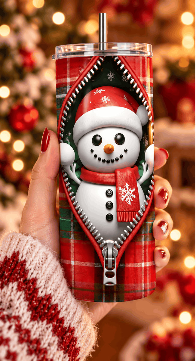 Tumbler bonhomme de neige zippé tenu dans la main, avec pull de Noël rouge et blanc et guirlandes en arrière-plan