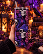 Main tenant le tumbler crâne sorcière et fleurs violettes avec paille, décor Halloween avec corbeau, bougies et citrouilles