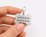 Verso d'une médaille chien en forme d'os tenu en main montrant deux numéros de téléphone gravés
